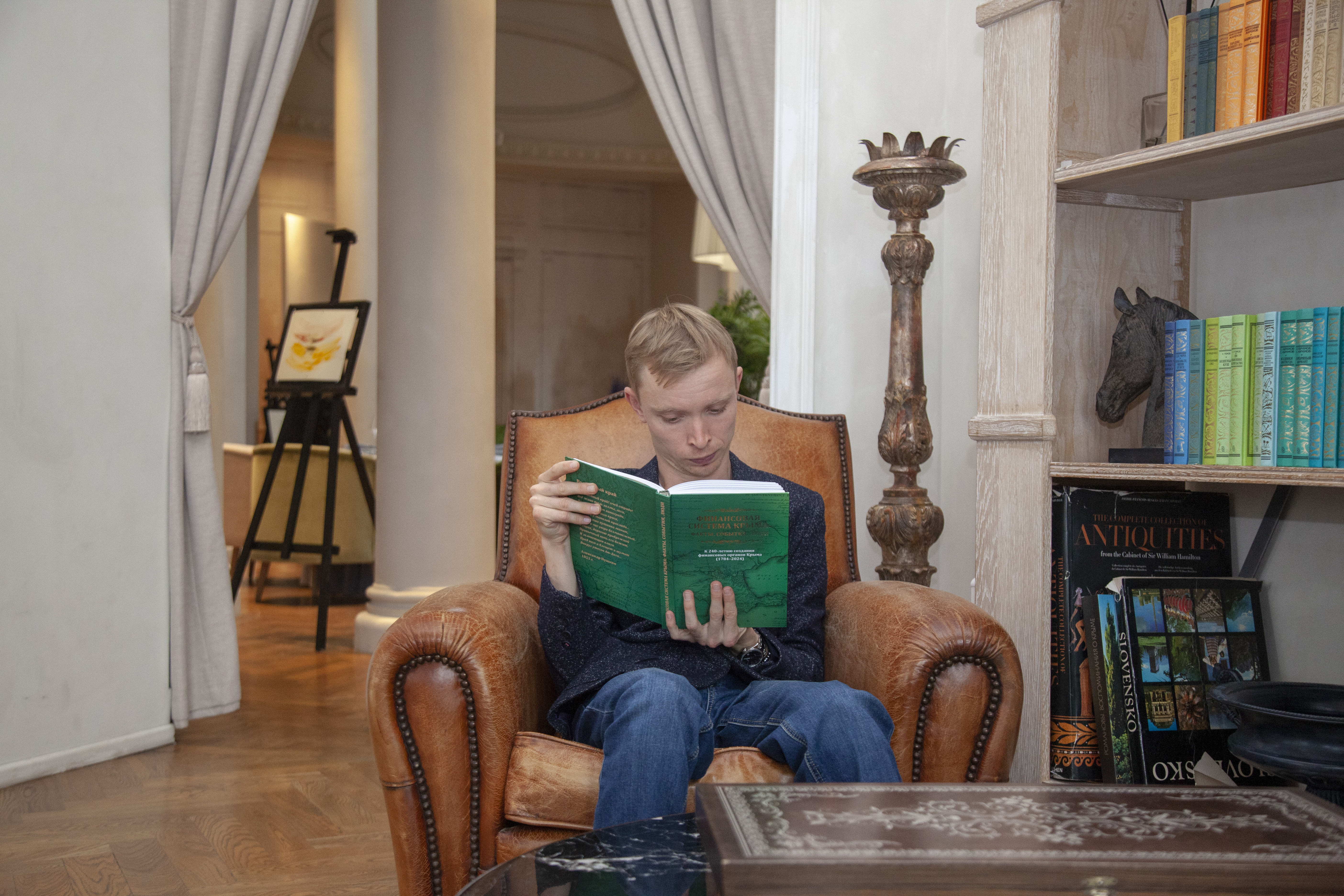 Андрей Малов читает книгу в кресле